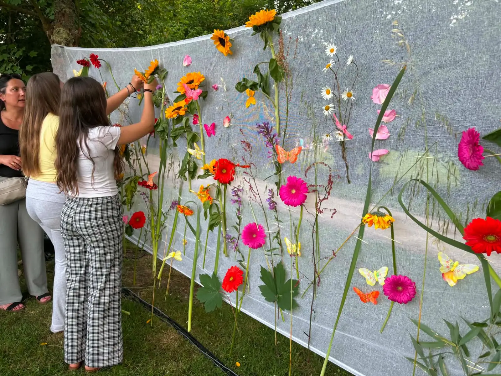 Des participantes piquent leurs fleurs sur le mur fleuri collectif.
