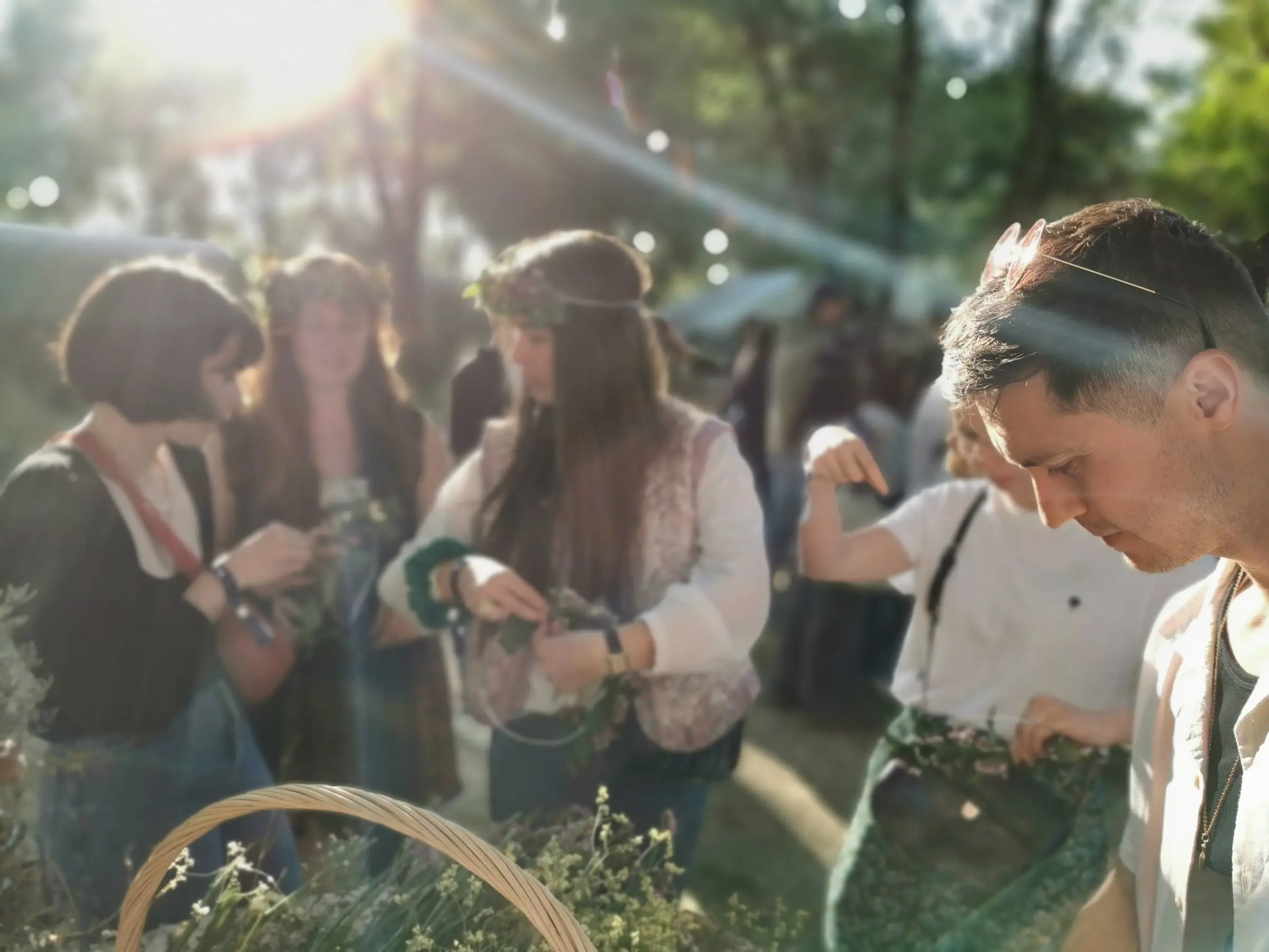 Dans un jardin baigné de soleil, des participantes tressent leur couronne de fleurs.