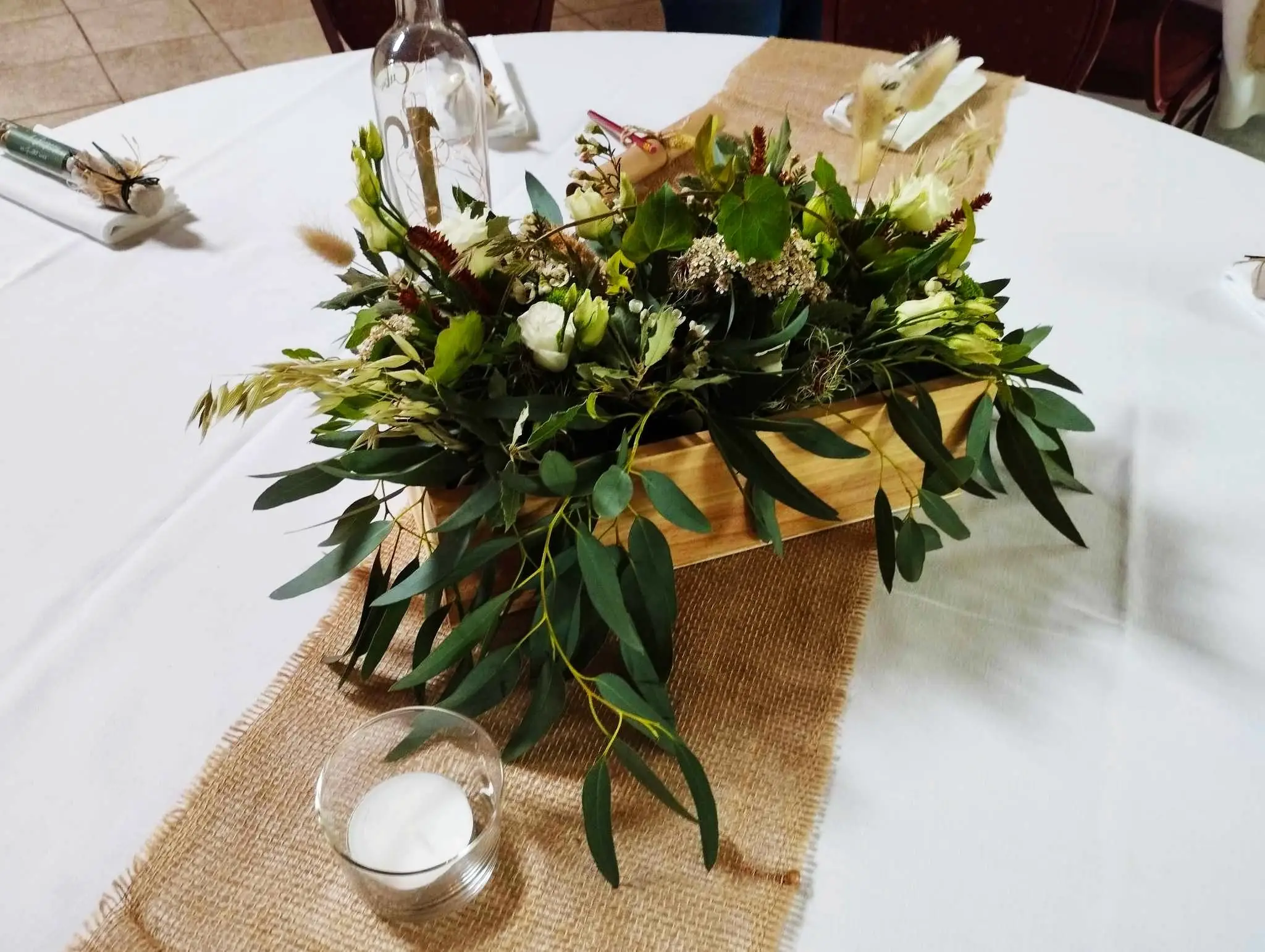 Centre de table posé sur un chemin en jute, entre deux bougies.