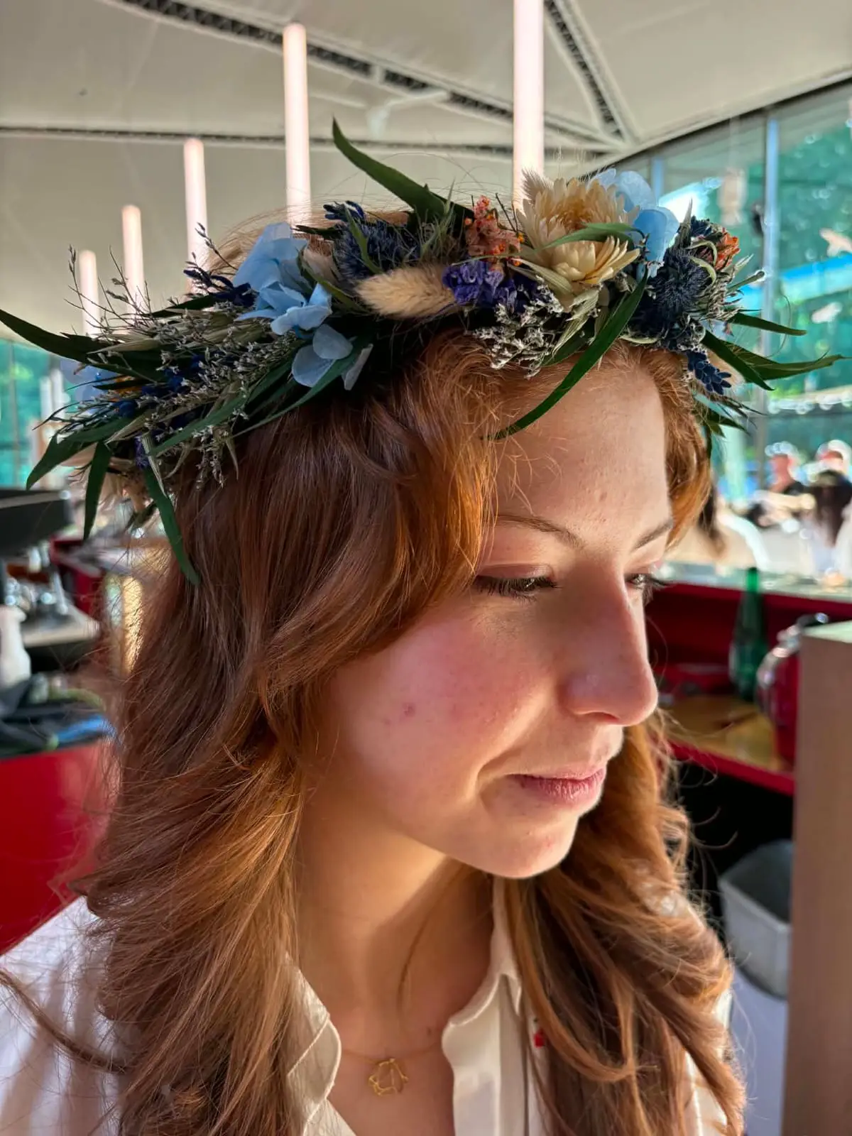Couronne de fleurs séchées bleues, blanches et dorées, vue de profil.